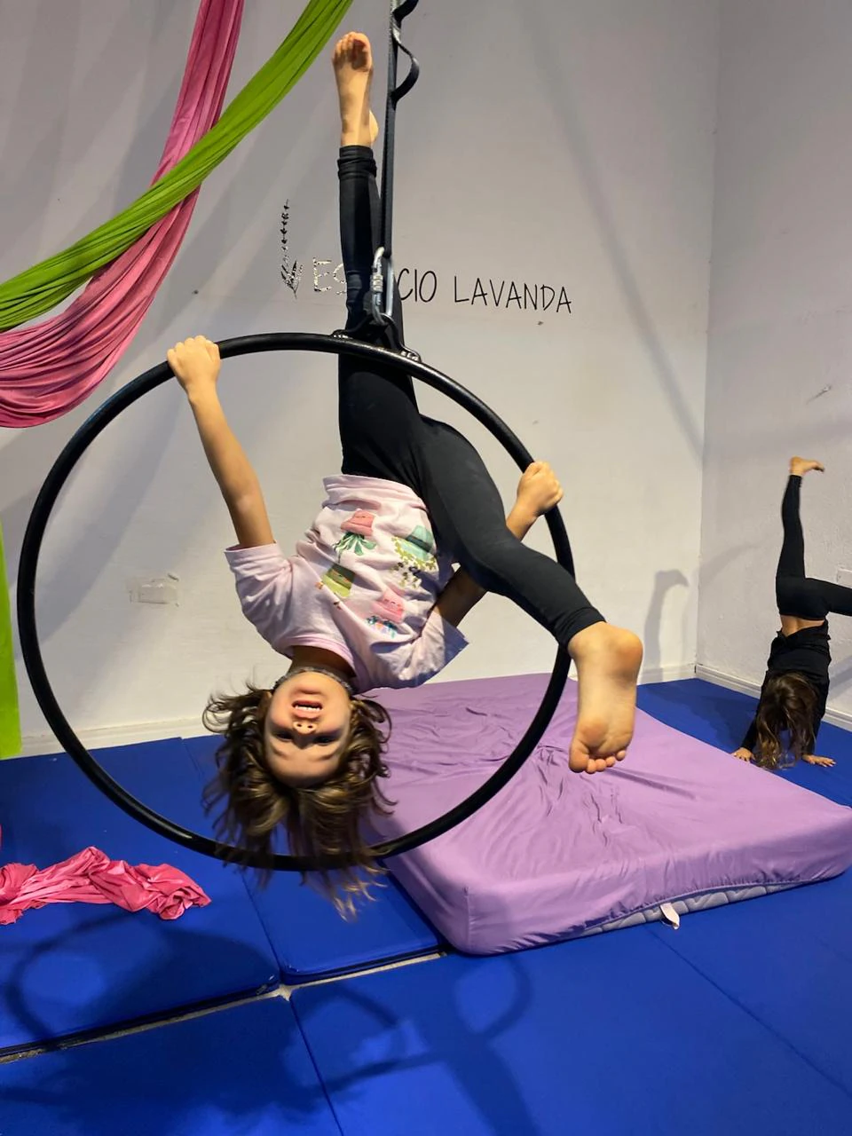 Nena haciendo acrobacia cabeza abajo en el aro